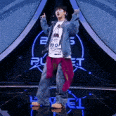 a man in a denim jacket is standing on a stage in front of a planet logo