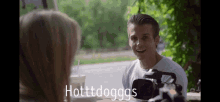 a man sitting at a table talking to a woman with the words hotttdogggs written below him