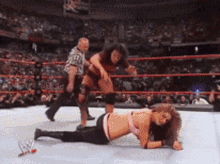 two women are wrestling in a ring with a referee