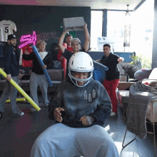 a man wearing a football helmet holds a brick above his head