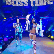 a man and a woman are walking down a runway with the word boss time behind them
