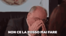 a man in a suit is covering his face with his hands and the words non ce la posso mai fare are written above him .