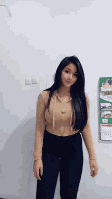 a woman is standing in front of a calendar on the wall .
