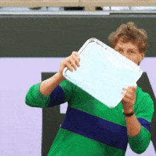 a man in a green and blue shirt is holding a tray