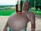 a shirtless man holds a bottle of velveeta vodka on his stomach
