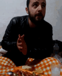 a man with a beard is sitting at a table with a checkered table cloth