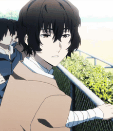 a boy with bandages on his wrists stands next to a fence