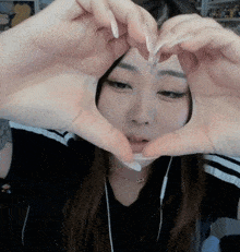 a woman is making a heart with her hands .