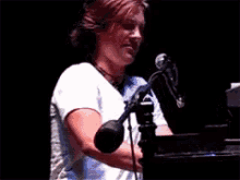 a woman in a white shirt is singing into a microphone on a stage