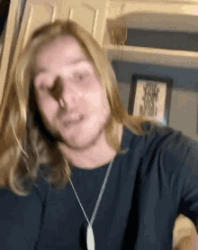 a man with long blonde hair is wearing a blue shirt