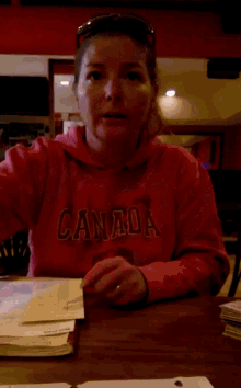 a woman sitting at a table wearing a red sweatshirt that says abercrombie & fitch