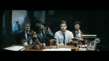 a group of men are sitting at a desk in front of a clock that says " ii "