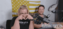a man in a dark web shirt is making a heart shape with his hands