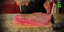 a person is cutting a piece of pink cake with the number 6 on the bottom