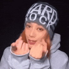 a woman wearing a beanie and a hoodie is making a face .