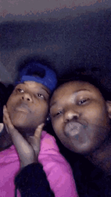 two girls are posing for a picture and one has a blue hat on her head .