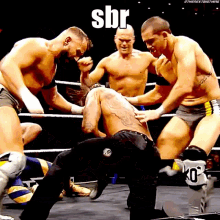 a group of men are wrestling in a ring and one of them has the word sbr on his chest