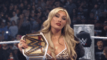 a woman in a wrestling ring holds a wwe championship belt