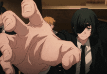a man in a suit and tie holds out his hand towards the camera