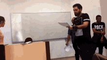 a man in a black shirt with the word rock on it is holding a piece of paper