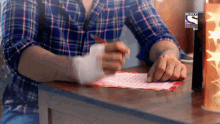 a man in a plaid shirt is writing on a piece of paper that says sony