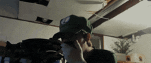 a person wearing a green hat with a blue patch on the front