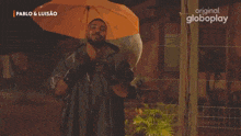 a man in a raincoat is holding a yellow umbrella in the rain .