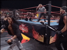 a man is standing in a wrestling ring holding a microphone and a gun .