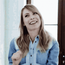 a woman in a blue shirt is smiling and pointing at something