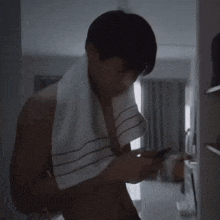 a man with a towel around his neck is looking at his phone