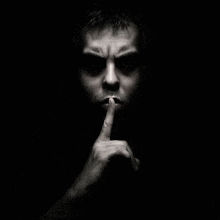 a man is making a shhh gesture with his finger to his mouth .