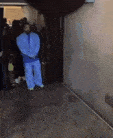 a man in a blue suit is standing in a hallway surrounded by people