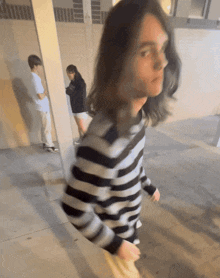 a man with long hair is wearing a striped shirt