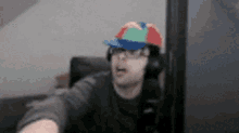 a man wearing a colorful hat and headphones is sitting in front of a computer .