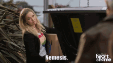 a woman holding a box that says nemesis on the bottom