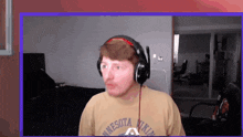 a man wearing headphones and a minnesota shirt looks at the camera