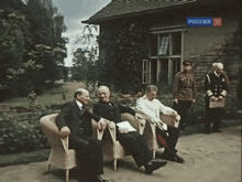 a group of men are sitting in front of a building with a sign that says " russia " on it