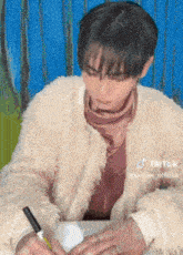 a person wearing a fur coat is writing on a piece of paper .