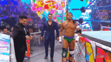 a group of men are standing in a wrestling ring talking to each other .