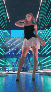 a woman in a black top and a white skirt is dancing