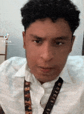 a man with curly hair is wearing a white shirt and a lanyard that says where .