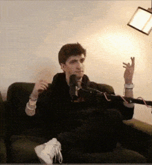 a man is sitting on a couch in front of a microphone and talking into it .