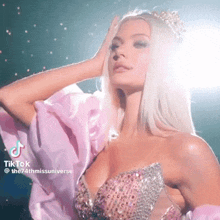 a woman is wearing a pink dress and a tiara .