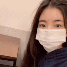 a young woman wearing a face mask is taking a selfie .