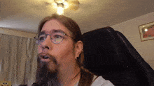 a man with glasses and a beard is sitting in a black chair