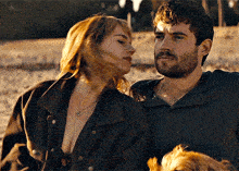 a man and a woman are sitting next to each other with their arms around each other