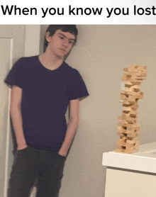 a man in a purple shirt stands next to a stack of wooden blocks with the caption when you know you lost