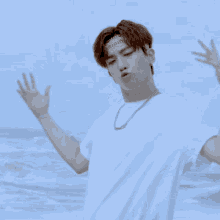 a young man wearing a headband and a necklace is standing on the beach