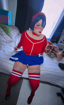 a woman is sitting on a bed wearing a red and blue outfit