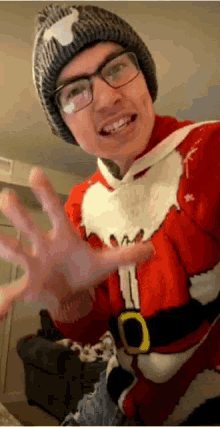 a man wearing a santa sweater and a beanie is waving